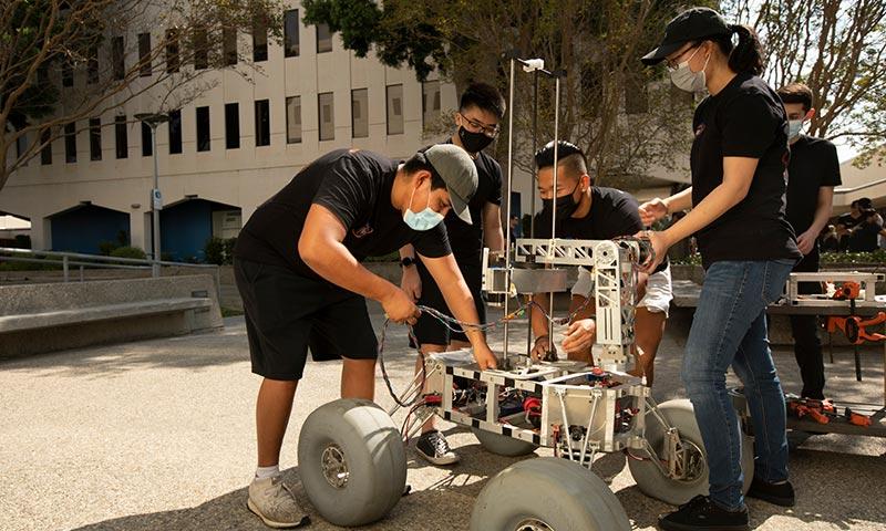 工程专业的学生和教师正在检查一个机械样机